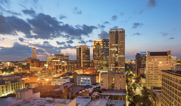 Evening skyline of downtown Birmingham, Alabama, with illuminated office buildings and city lights at sunset.