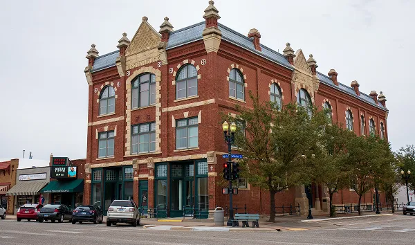 McPherson, Kansas, USA - July 27, 2022. Exterior of old opera house with colorful brick work. McPherson Opera House with colorful exterior and pale sky. Red brick, tan highlights and ornate roofing.